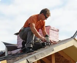 Charlotte's Best Roofing crew member fastening shingles with a nail gun at the roof edge