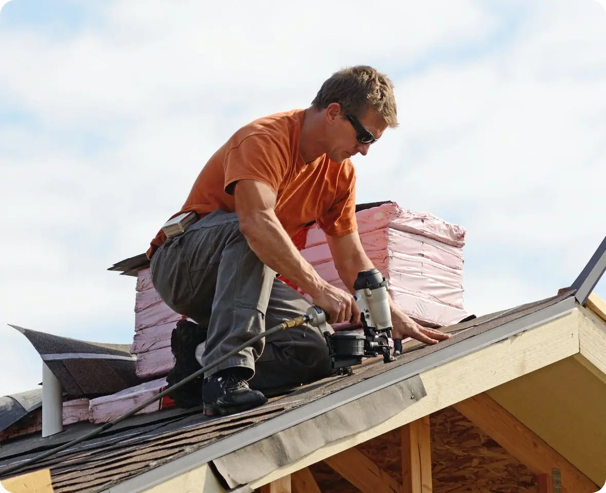 Charlotte's Best Roofing crew member fastening shingles with a nail gun at the roof edge