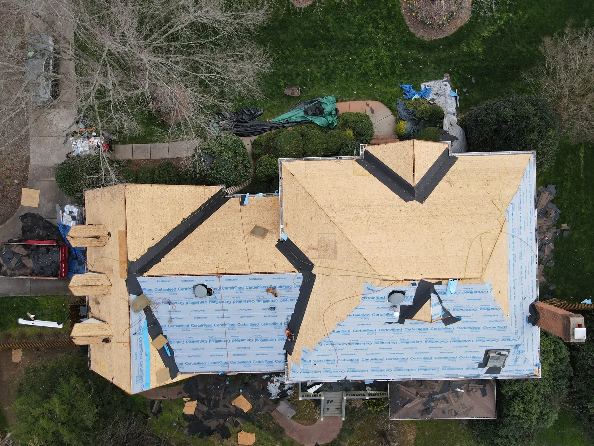 Aerial view of a house mid roof replacement with sections stripped to the decking