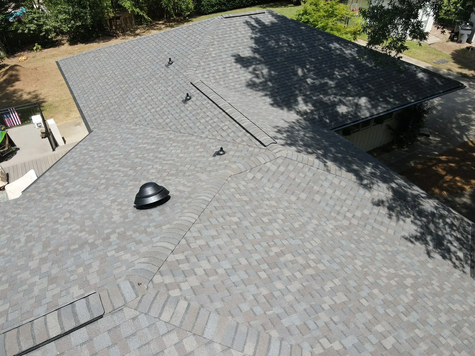 Aerial view of a gray architectural shingle roof with ridge caps and roof vents