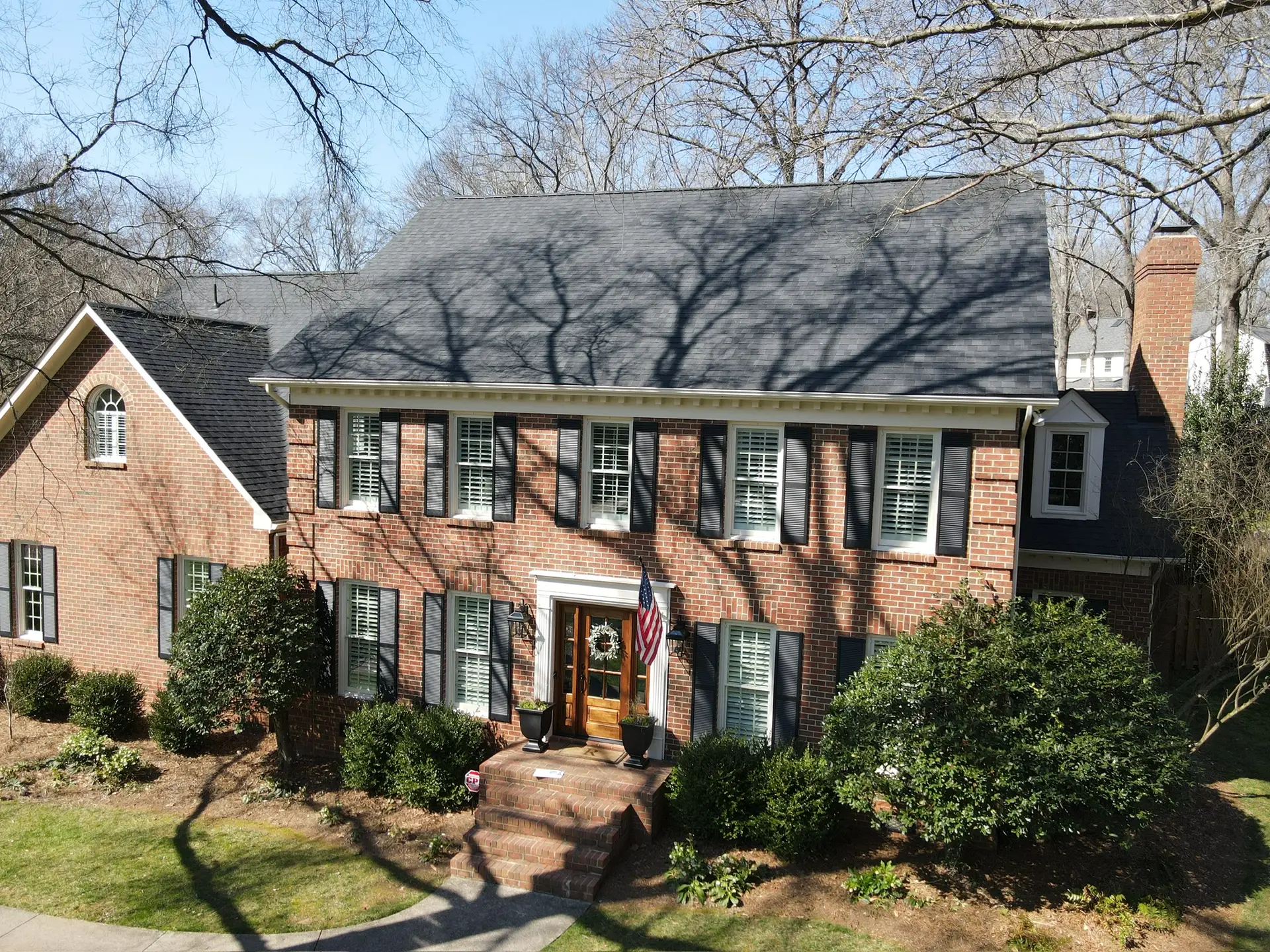 Two-story brick colonial with a new gray architectural shingle roof and dark shutters