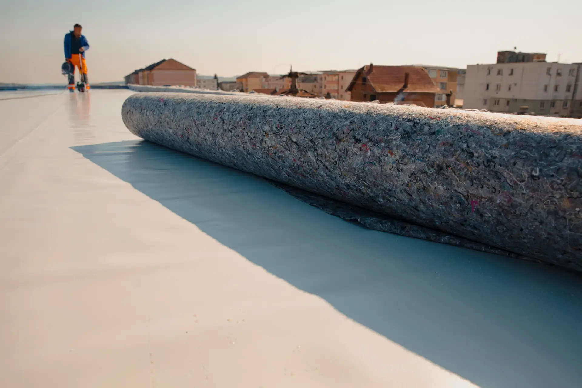 Roll of EPDM roofing membrane laid out on a commercial flat roof before installation