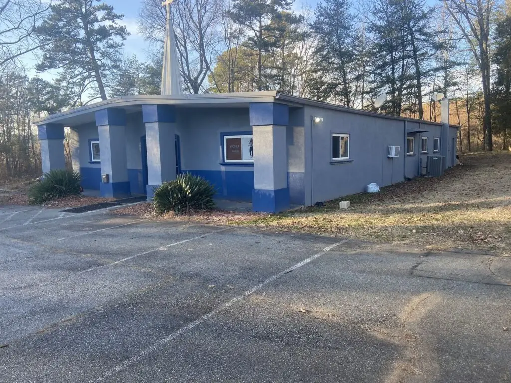 Blue commercial building with a low-slope roof and a large parking lot