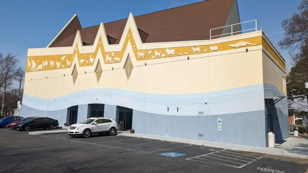 Yellow and blue commercial building with a completed roof and customer parking
