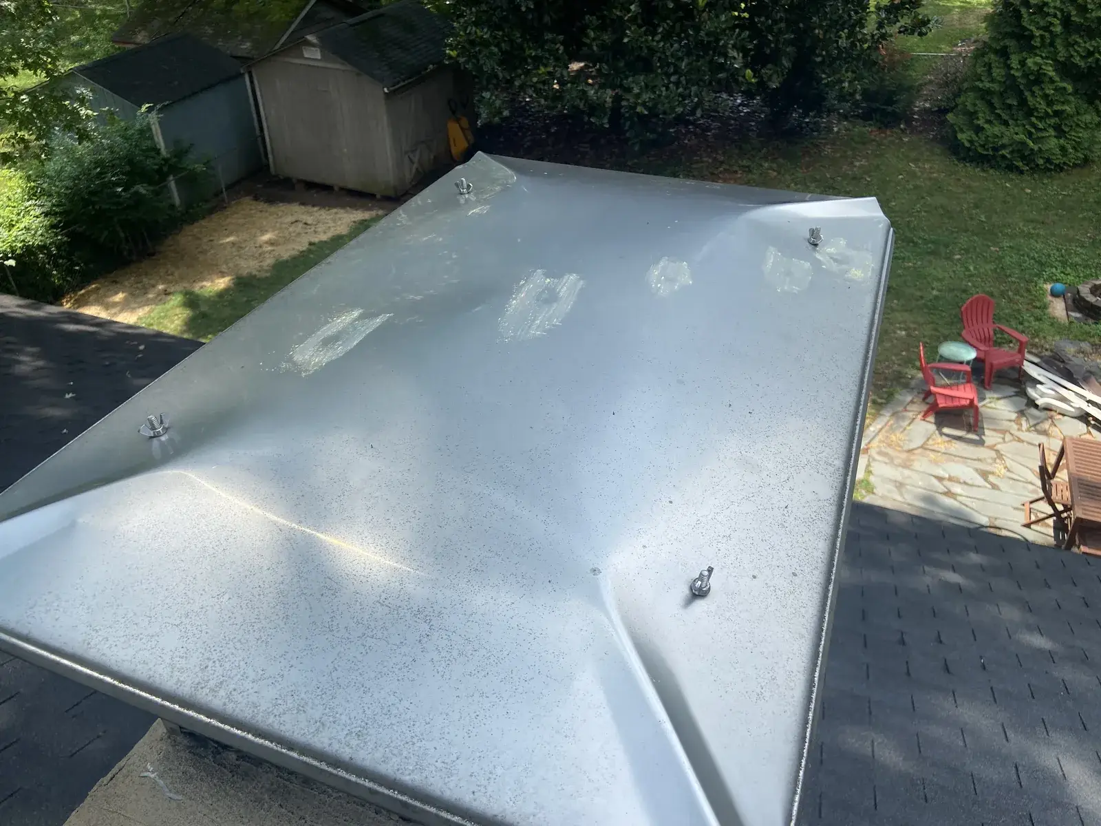 Hail-dented sheet metal roof panel on a home