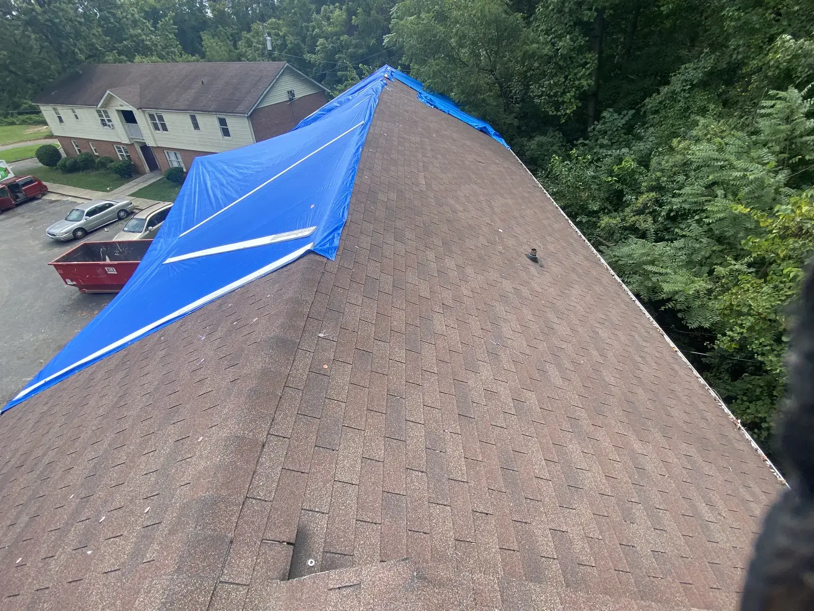 Blue emergency tarp over a storm-damaged roof section