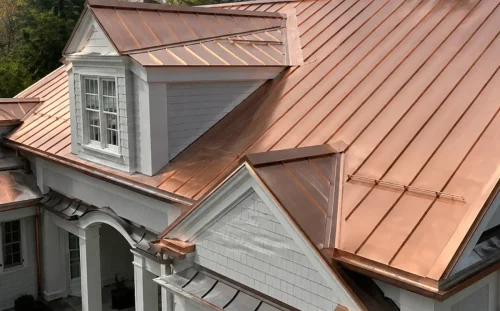 Aerial view of a standing seam copper roof with multiple dormers and gables on a stately home with white columns and a covered entrance