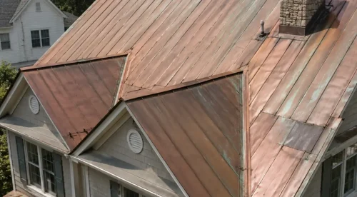 Aerial view of a finished standing seam copper roof with two dormers, showing natural patina and weathering across the panels