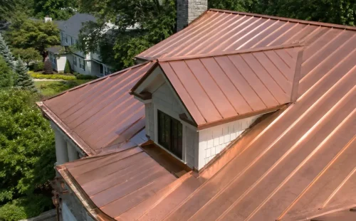 Aerial view of a house with a complete standing seam copper roof and dormer, surrounded by mature trees